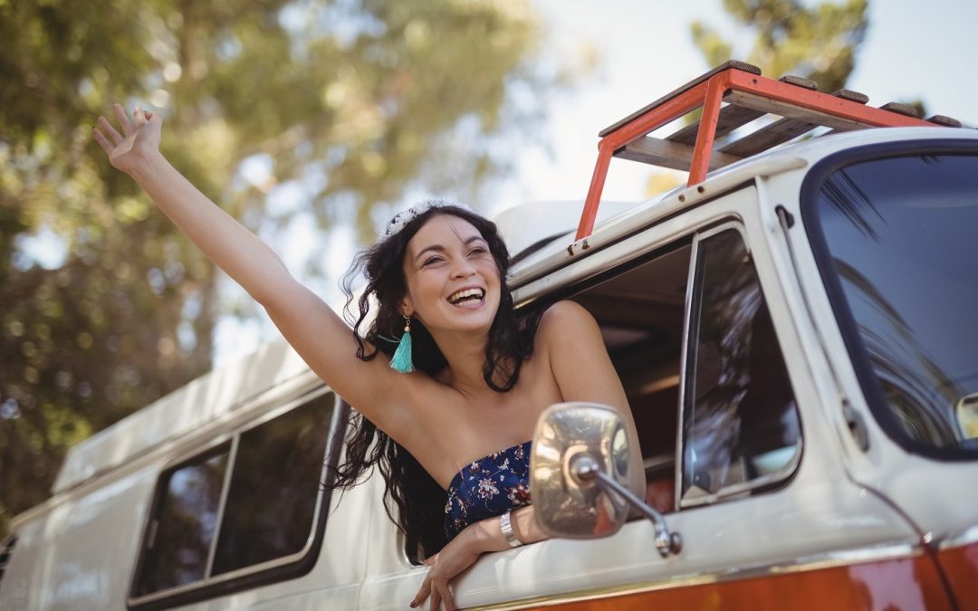 mulher acenando apoiada na porta de um motorhome